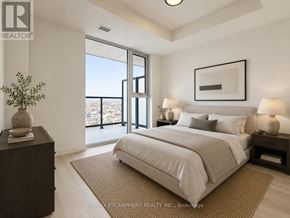 Burlington (Alton) condo for rent - A bedroom with a large bed, a nightstand, and a window overlooking a cityscape.