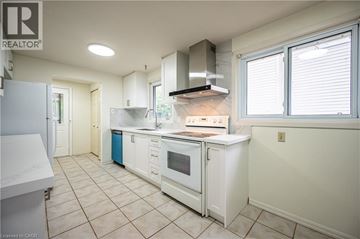 Kitchener apartment for rent - A white kitchen with a refrigerator on the left and a stove top oven in the middle.