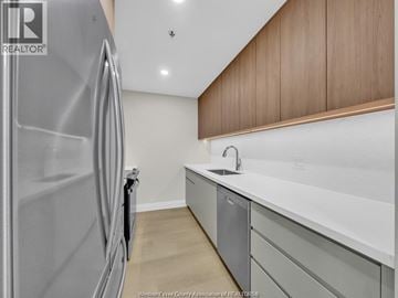 Windsor condo for rent - A modern kitchen with a stainless steel refrigerator and wooden cabinets.