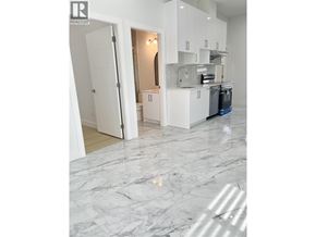 Vancouver apartment for rent - A white kitchen with a marble floor and a realtor logo.