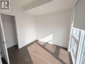 Toronto (Bay Street Corridor) condo for rent - A room with a wooden floor and white walls, with a door on the left and a window on the right.