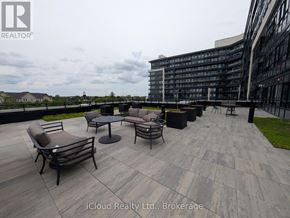 Oakville (Go Glenorchy) condo for rent - A patio area with chairs and a table in front of a modern building.