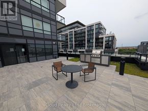 Oakville (Go Glenorchy) condo for rent - A modern building with a glass facade and a patio with a table and chairs.