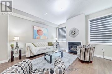 Clarington (Bowmanville) apartment for rent - A living room with a fireplace, a couch, a chair, and a painting on the wall.