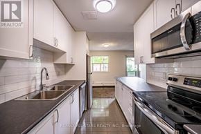 Whitchurch-Stouffville (Stouffville) multi-family for rent - A kitchen with white cabinets and black countertops.