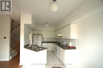 Markham (Unionville) townhouse for rent - A kitchen with white cabinets and a black counter top.