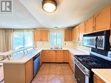 Barrie (Northwest) apartment for rent - A kitchen with wooden cabinets and a black stove top oven.