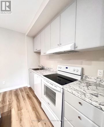 St. Catharines (Oakdale) condo for rent - A white kitchen with a stove top oven and a marble counter top.