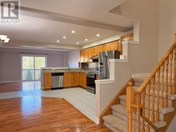 Brampton (Fletcher's Meadow) apartment for rent - A spacious kitchen with wooden cabinets and a staircase leading to the upper floor.