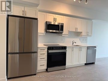 Toronto (Yorkdale-Glen Park) condo for rent - A kitchen with a stainless steel refrigerator, microwave, oven, and cabinets.