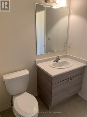 Kitchener townhouse for rent - A white toilet sits next to a sink in a bathroom.