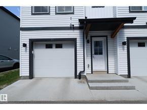 Edmonton townhouse for rent - A white house with a black garage door and a black car parked in front.