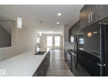 Edmonton townhouse for rent - A modern kitchen with a black refrigerator and wooden cabinets.