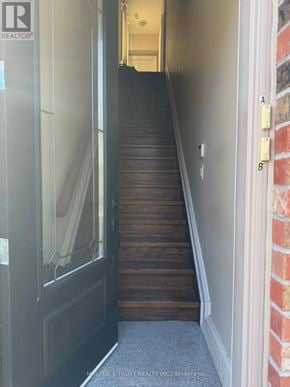 King (King City) apartment for rent - A hallway with a wooden staircase leading to a door.
