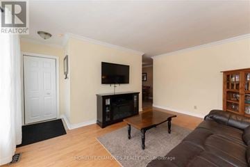 Halton Hills (Georgetown) apartment for rent - A living room with a black leather couch and a flat screen TV mounted above a fireplace.
