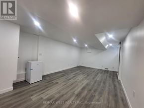 Toronto (Broadview North) triplex for rent - A spacious room with a wood floor and white walls.