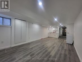 Toronto (Broadview North) triplex for rent - A spacious room with wooden flooring and white walls, with a door on the right side.