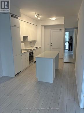 Mississauga (City Centre) condo for rent - A realtor is showing a white kitchen with a countertop and a person in the background.