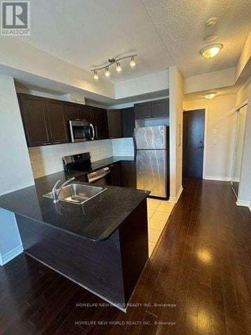 Mississauga (City Centre) condo for rent - A kitchen with dark wood cabinets and a black countertop.