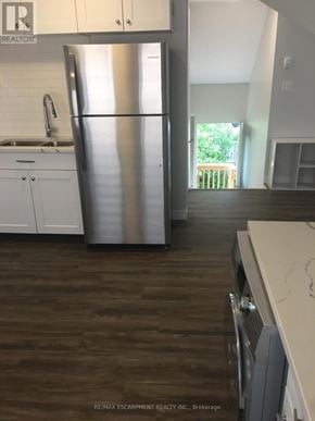 Kitchener duplex for rent - A kitchen with a stainless steel refrigerator and wooden floors.