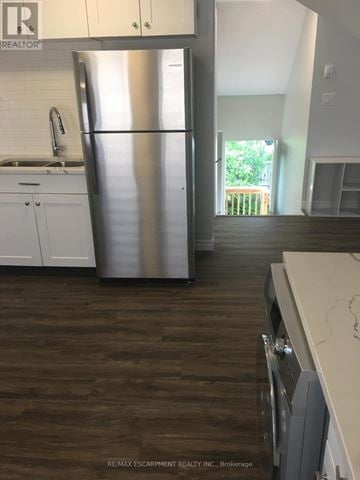 Kitchener duplex for rent - A kitchen with a stainless steel refrigerator and wooden floors.