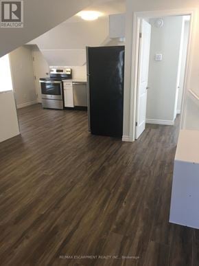 Kitchener duplex for rent - A kitchen with a black fridge and wooden floors.