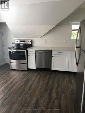 Kitchener duplex for rent - A kitchen with white cabinets and a black stove top oven.