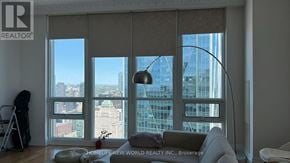 Toronto (Waterfront Communities) condo for rent - A living room with a large window overlooking a cityscape.