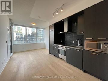 Toronto (Waterfront Communities) condo for rent - A modern kitchen with black cabinets and stainless steel appliances.
