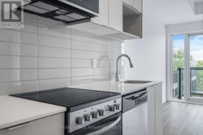 Toronto (West Hill) condo for rent - A modern kitchen with a black stove top oven and white cabinets.