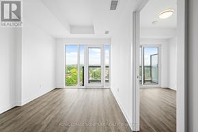 Toronto (West Hill) condo for rent - A spacious room with wooden floors and large windows overlooking a garden.