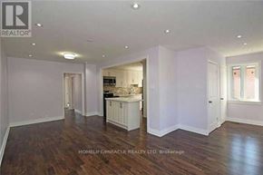 Brampton (Brampton South) apartment for rent - A spacious room with wooden floors and white walls, featuring a kitchen area with a sink and cabinets.
