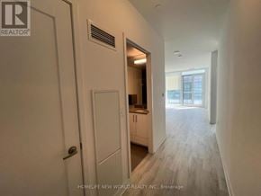 Toronto (Waterfront Communities) condo for rent - A hallway with a door on the left and a kitchen area visible through the door.