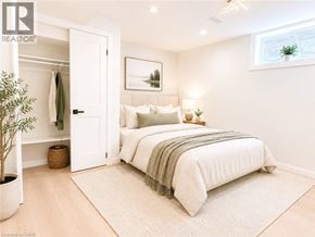 Dundas apartment for rent - A bedroom with a large bed and a plant in a pot.