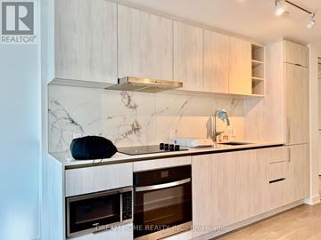 Toronto (Bay Street Corridor) condo for rent - A modern kitchen with wooden cabinets and marble countertops.