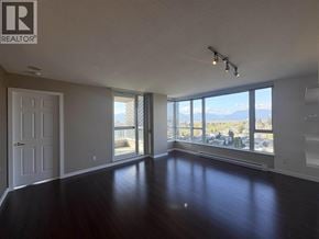 Vancouver apartment for rent - A spacious room with a view of the mountains outside the window.