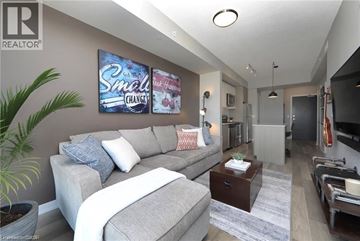 Burlington condo for rent - A living room with a grey couch and a poster on the wall.