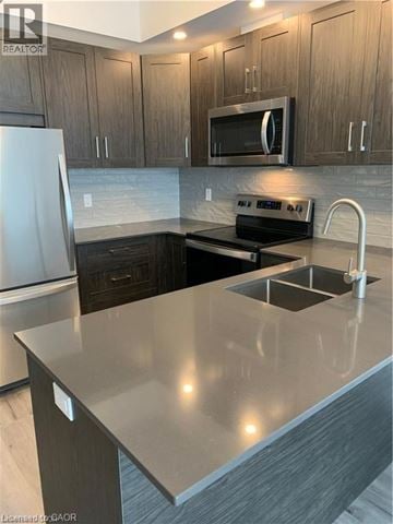 Kitchener condo for rent - A modern kitchen with a stainless steel refrigerator and a microwave above the stove.