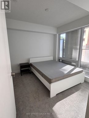 Toronto (Humber Heights) condo for rent - A bedroom with a bed, nightstand, and window.