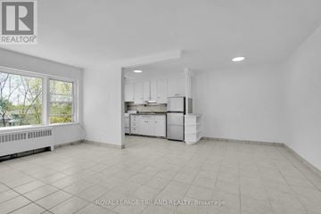 London East (East M) multi-family for rent - A white kitchen with white cabinets and appliances in a white room with white tiled flooring.