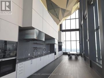 Toronto (Waterfront Communities) condo for rent - A modern kitchen with white cabinets and a large window.