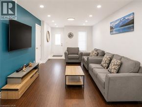 Kitchener apartment for rent - A living room with a grey couch and a flat screen TV mounted on the wall.