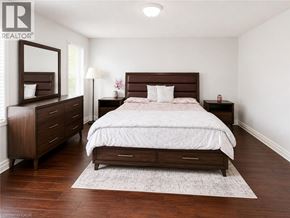 Kitchener apartment for rent - A bedroom with a large bed, a dresser, and a nightstand.