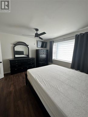 St. John's apartment for rent - A bedroom with a bed, dresser, mirror, and a ceiling fan.