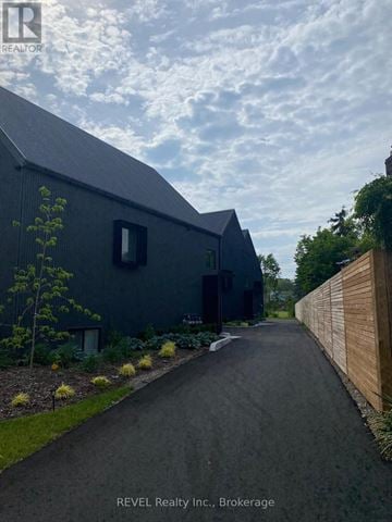 Niagara Falls (Cherrywood) apartment for rent - A modern house with a dark grey exterior and a wooden fence on the right side.