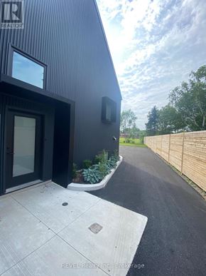 Niagara Falls (Cherrywood) apartment for rent - A modern house with a black exterior and a wooden fence in the background.