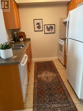 Mississauga (City Centre) condo for rent - A kitchen with a white fridge and wooden cabinets.