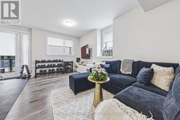 Burlington (Rose) townhouse for rent - A living room with a black couch and a wooden floor.