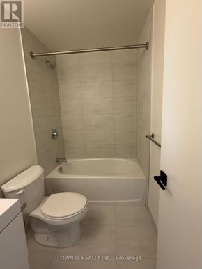 Brantford condo for rent - A white toilet and bathtub in a bathroom.