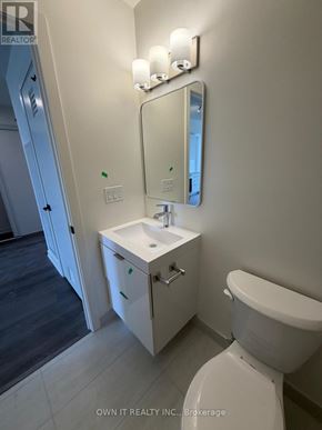 Brantford condo for rent - A white bathroom with a toilet, sink, and mirror.